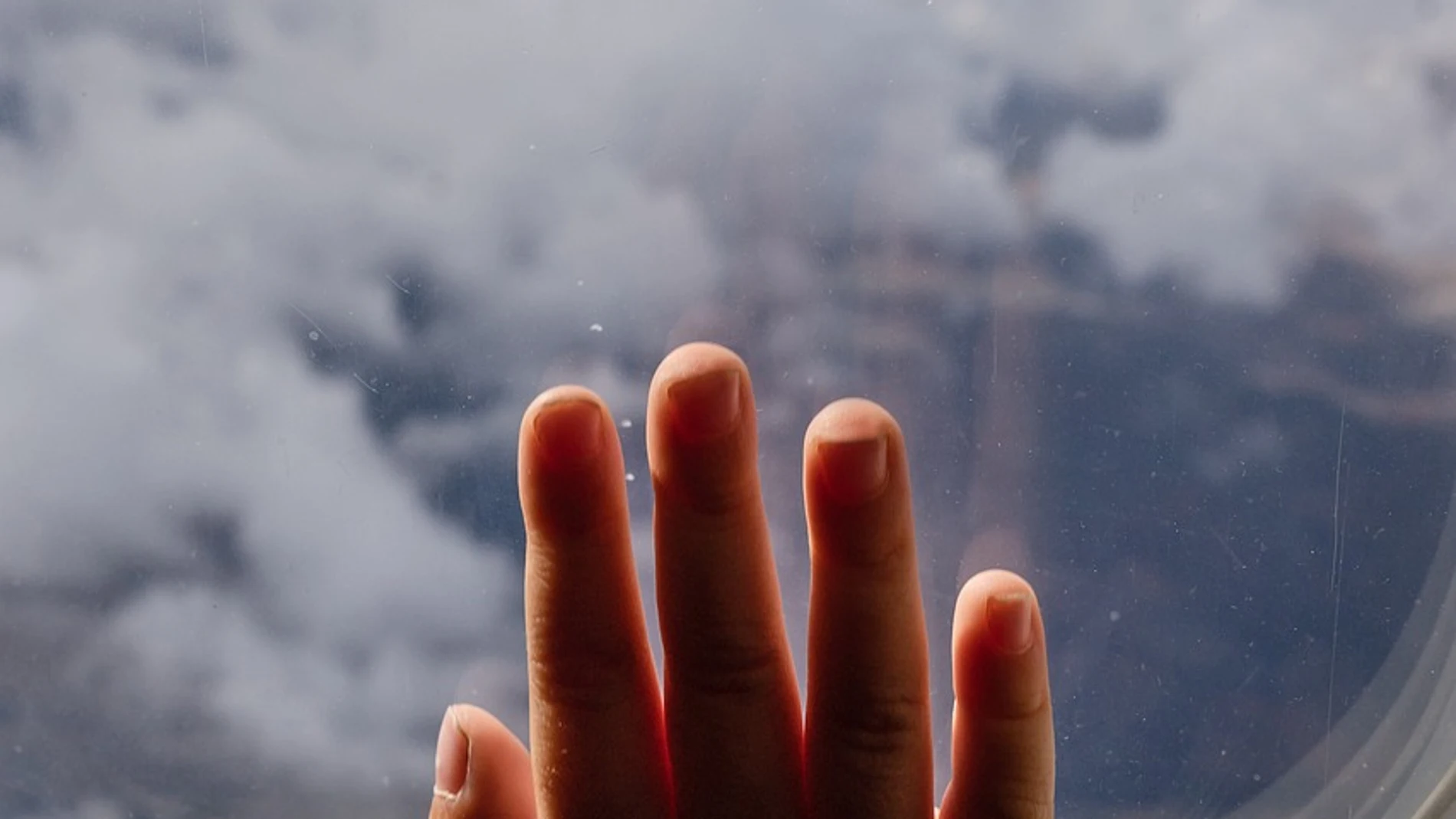 Imagen de la mano de un niño en la ventana de un avión