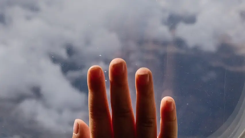 Imagen de la mano de un ni&ntilde;o en la ventana de un avi&oacute;n