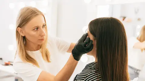 Una doctora revisa la piel del rostro de una paciente Una doctora revisa la piel del rostro de una paciente