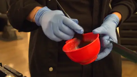 Una peluquera manejando el producto alisador Una peluquera manejando el producto alisador