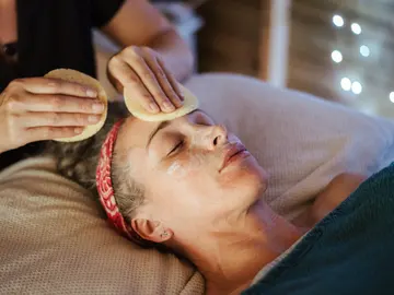 Una mujer recibiendo un tratamiento facial en un salón de belleza. Una mujer recibiendo un tratamiento facial en un salón de belleza.