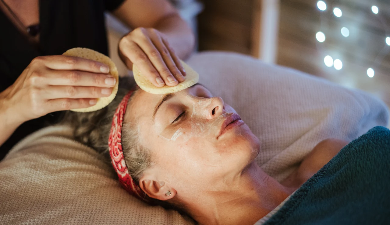 Una mujer recibiendo un tratamiento facial en un salón de belleza.