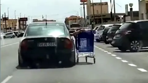 Circulan llevando un carro de la compra por la ventanilla del coche Circulan llevando un carro de la compra por la ventanilla del coche