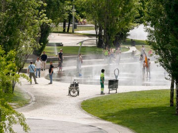 Varias personas disfrutan de los chorros de agua de Madrid Río