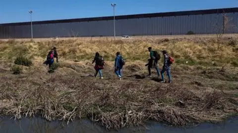 Migrantes caminando en la frontera de EEUU con México Migrantes caminando en la frontera de EEUU con México