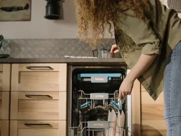 Mujer colocando los platos en el lavavajillas Mujer colocando los platos en el lavavajillas