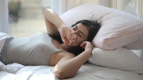 Mujer recostada sobre un par de almohadas Mujer recostada sobre un par de almohadas
