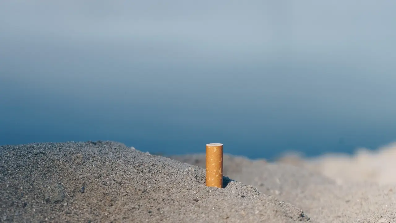 Colilla tirada en la arena de una playa Colilla tirada en la arena de una playa