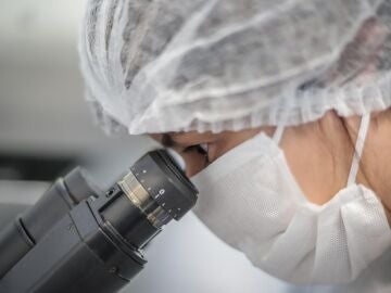 Científica mira a través de un microscopio en un laboratorio
