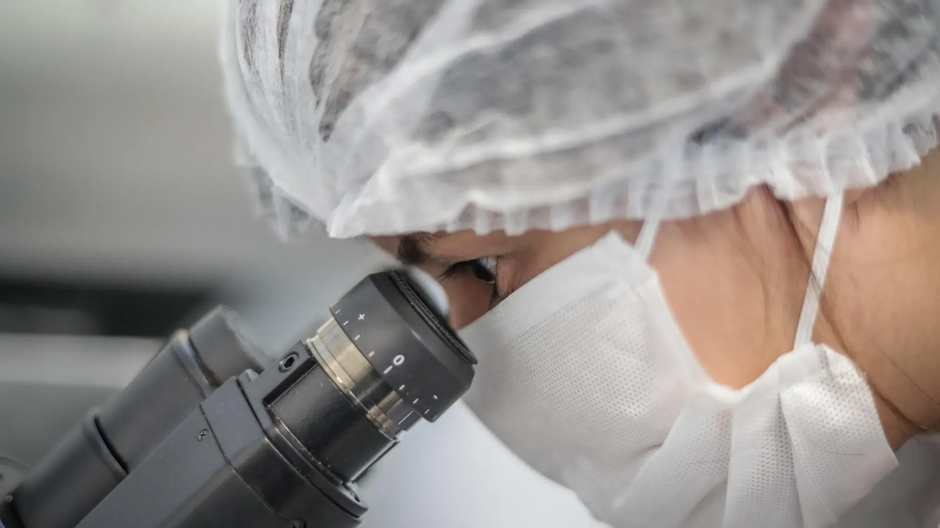 Científica mira a través de un microscopio en un laboratorio Científica mira a través de un microscopio en un laboratorio