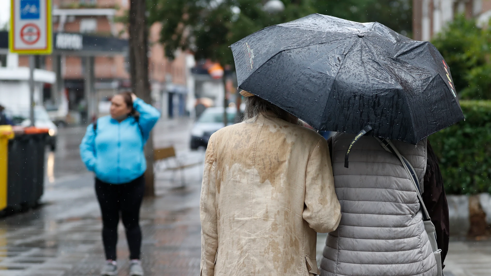 Dos personas se refugian de la lluvia con un paraguas 