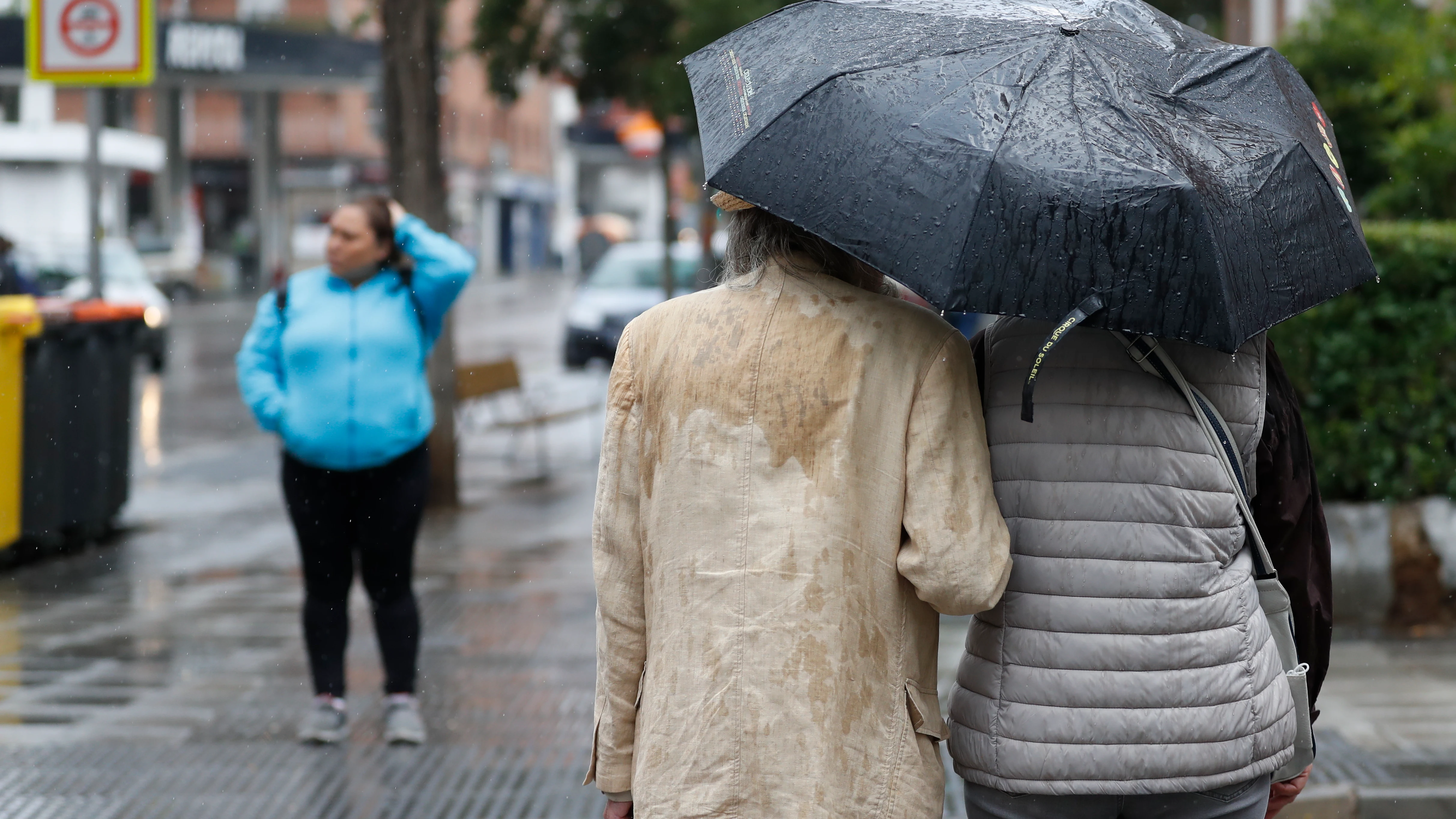 Dos personas se refugian de la lluvia con un paraguas Dos personas se refugian de la lluvia con un paraguas