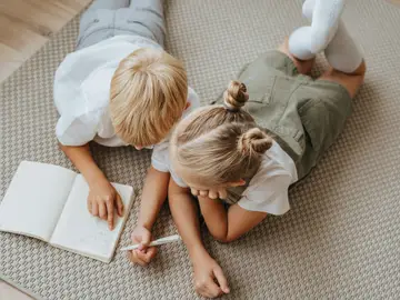 Dos niños escribiendo en una libreta