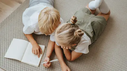 Dos niños escribiendo en una libreta Dos niños escribiendo en una libreta