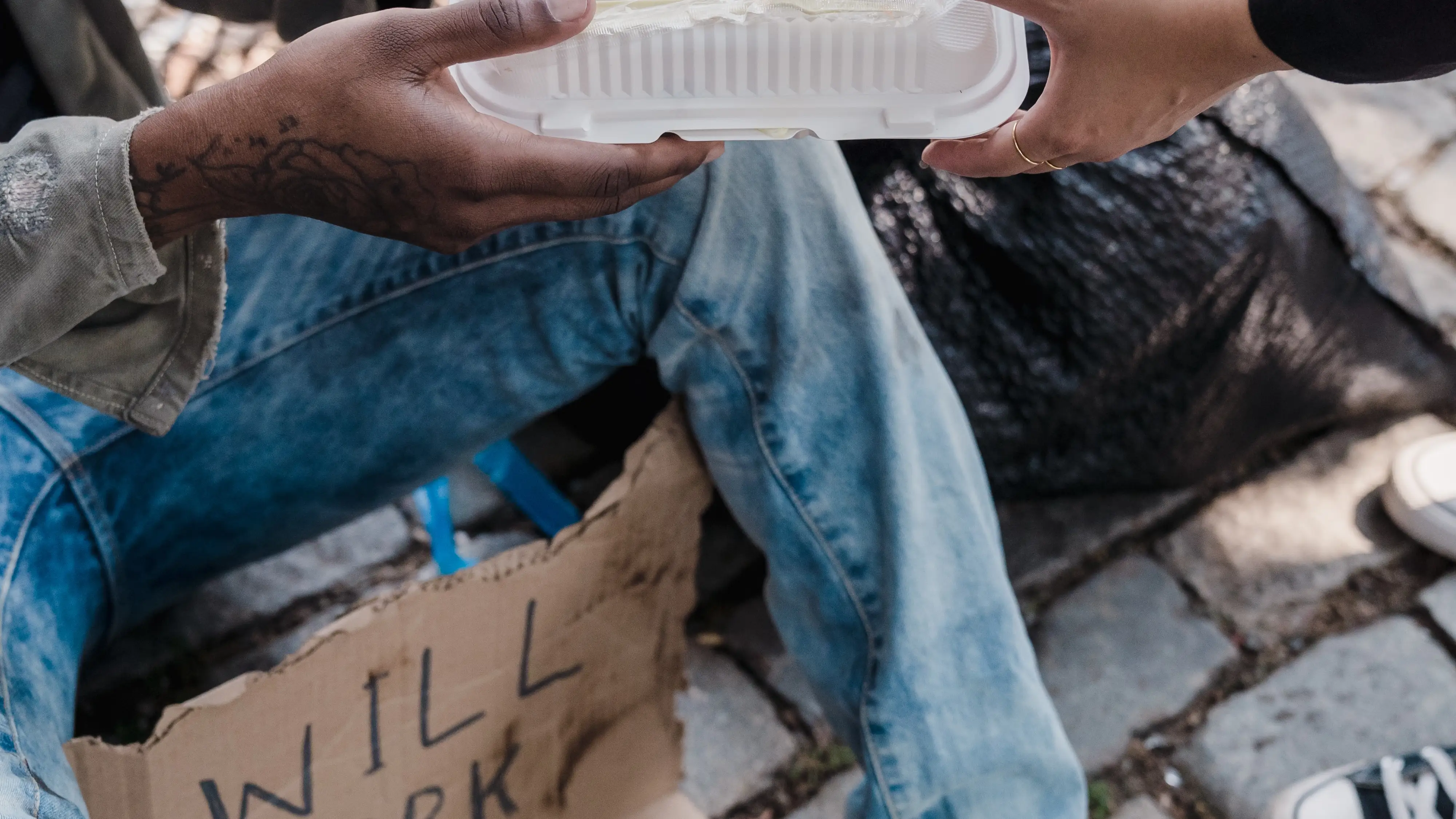 Persona dando comida a un indigente en la calle Persona dando comida a un indigente en la calle