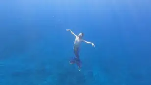 Un hombre practica mermaiding en el mar