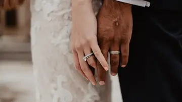 Dos novios se cogen de la mano en su boda