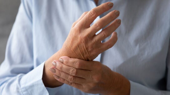 Se&ntilde;ora mayor masajeando la mano que sufre de concepto de artritis reumatoide
