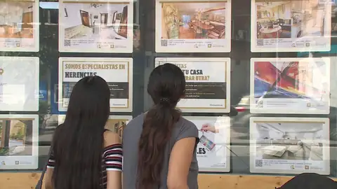 Personas mirando anuncios en el exterior de una inmobiliaria Personas mirando anuncios en el exterior de una inmobiliaria