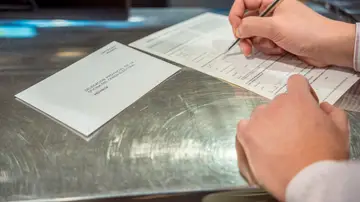 Una persona rellenado el voto por correo Una persona rellenado el voto por correo