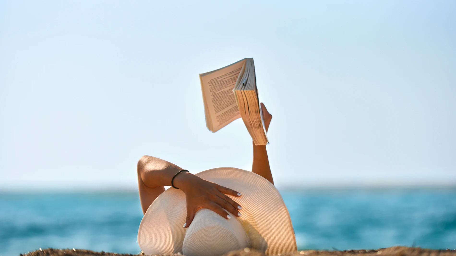 Una joven lee un libro en la playa