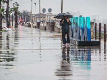 Una persona camina bajo la lluvia hoy, en el puerto de Ensenada en Baja California (México)