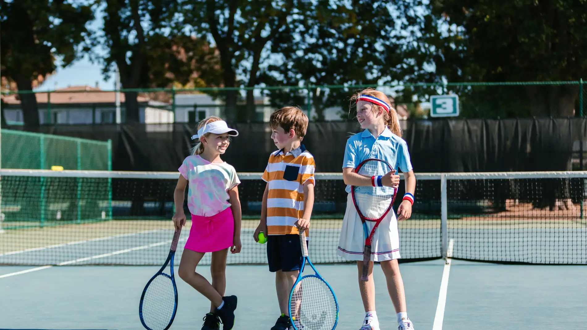 Niñas y niño jugando a tenis
