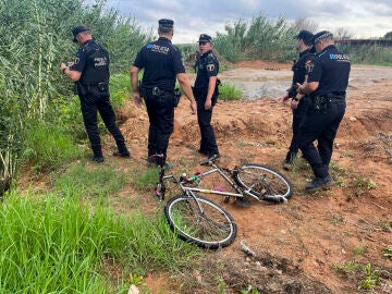 La Policía Local de paterna junto a la bicicleta del hombre arrastrado por el agua que intentó cruzar un barranco en Paterna.