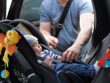 Papá colocando al bebé en una sillita de retención para el coche