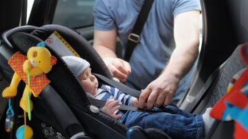 Papá colocando al bebé en una sillita de retención para el coche