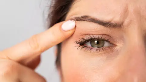 Mujer levantándose el párpado Mujer levantándose el párpado