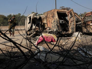 Un soldado israelí camina junto a un vehículo averiado en Gaza
