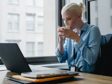 Mujer bebiendo de una taza delante del ordenador Mujer bebiendo de una taza delante del ordenador