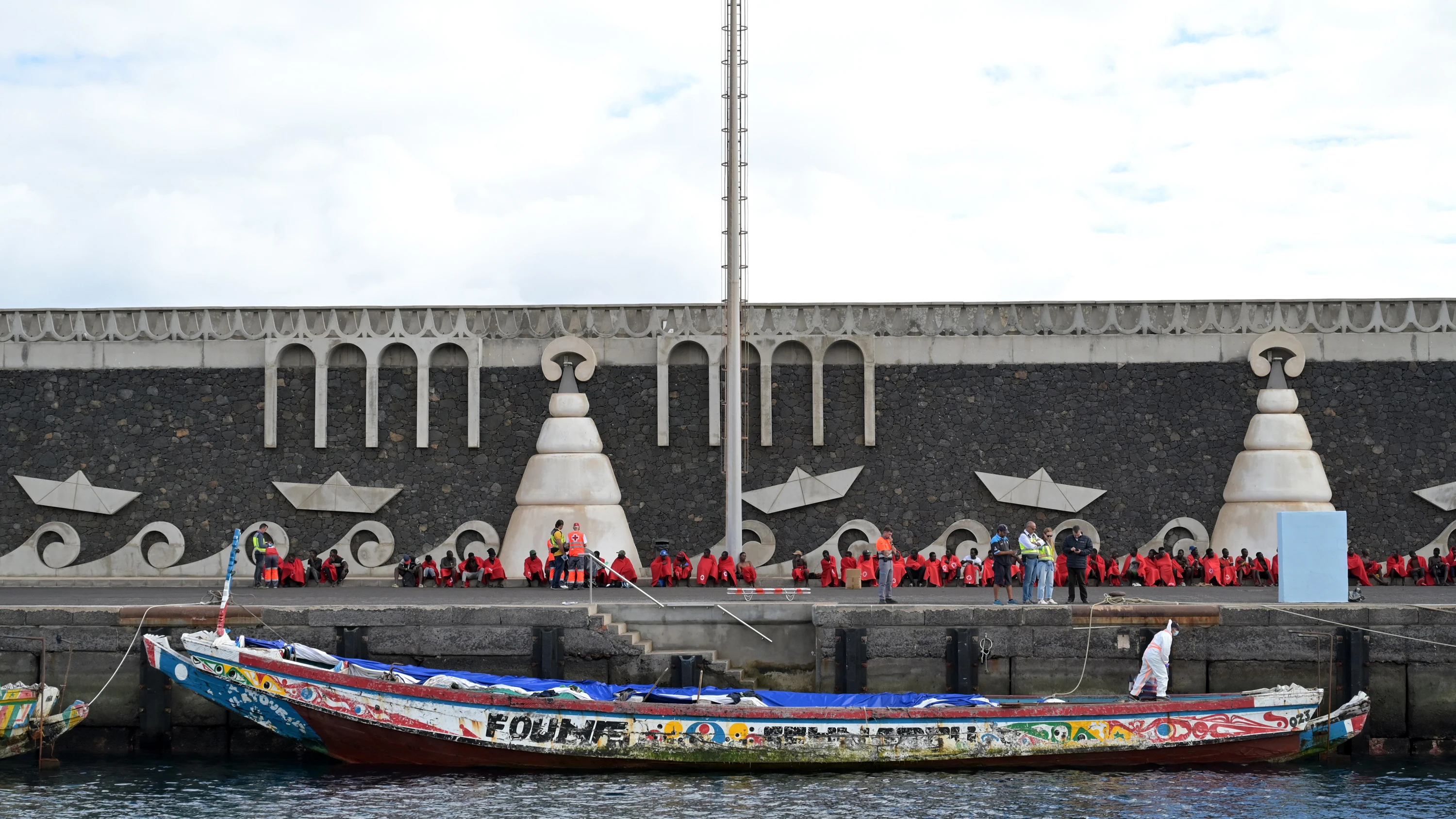 Decenas de migrantes, tras su llegada en un cayuco Decenas de migrantes, tras su llegada en un cayuco