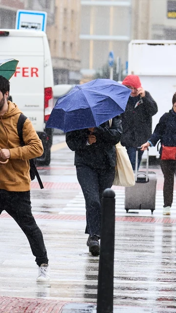 Varias personas se cubren de la lluvia y el viento con paraguas