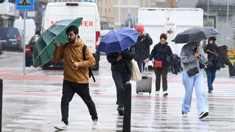 Varias personas se cubren de la lluvia y el viento con paraguas Varias personas se cubren de la lluvia y el viento con paraguas