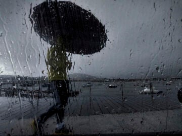 Un hombre con paraguas camina por el puerto de Pontedeume