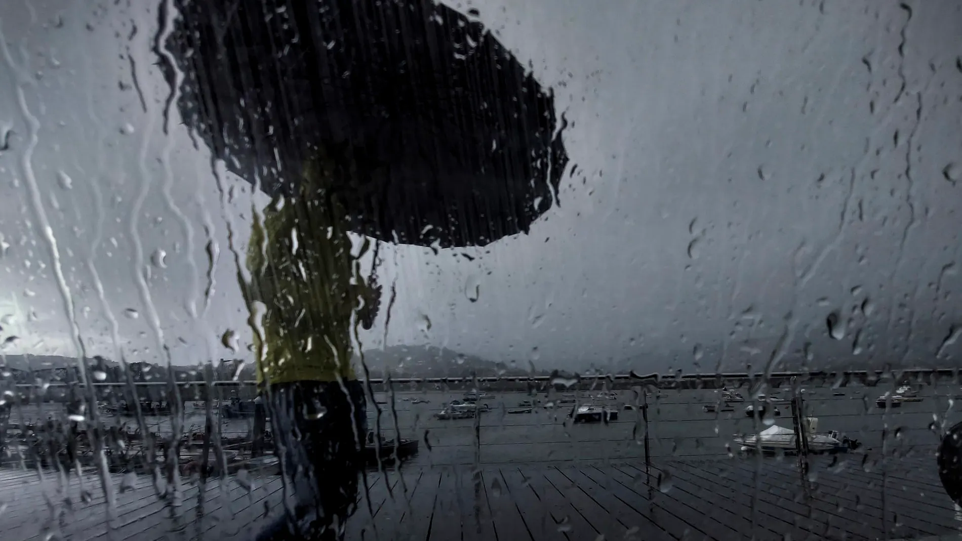 Un hombre con paraguas camina por el puerto de Pontedeume