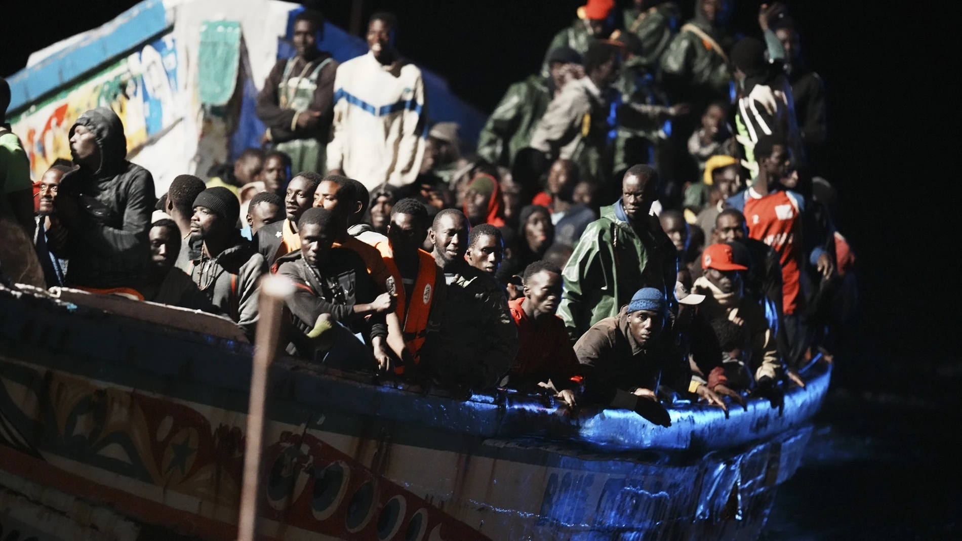 Decenas de personas en un cayuco a su llegada al muelle de La Restinga, en El Hierro
