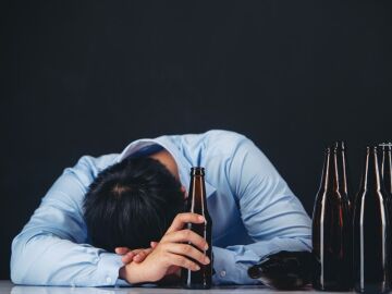 Hombre durmiendo con botellas de alcohol