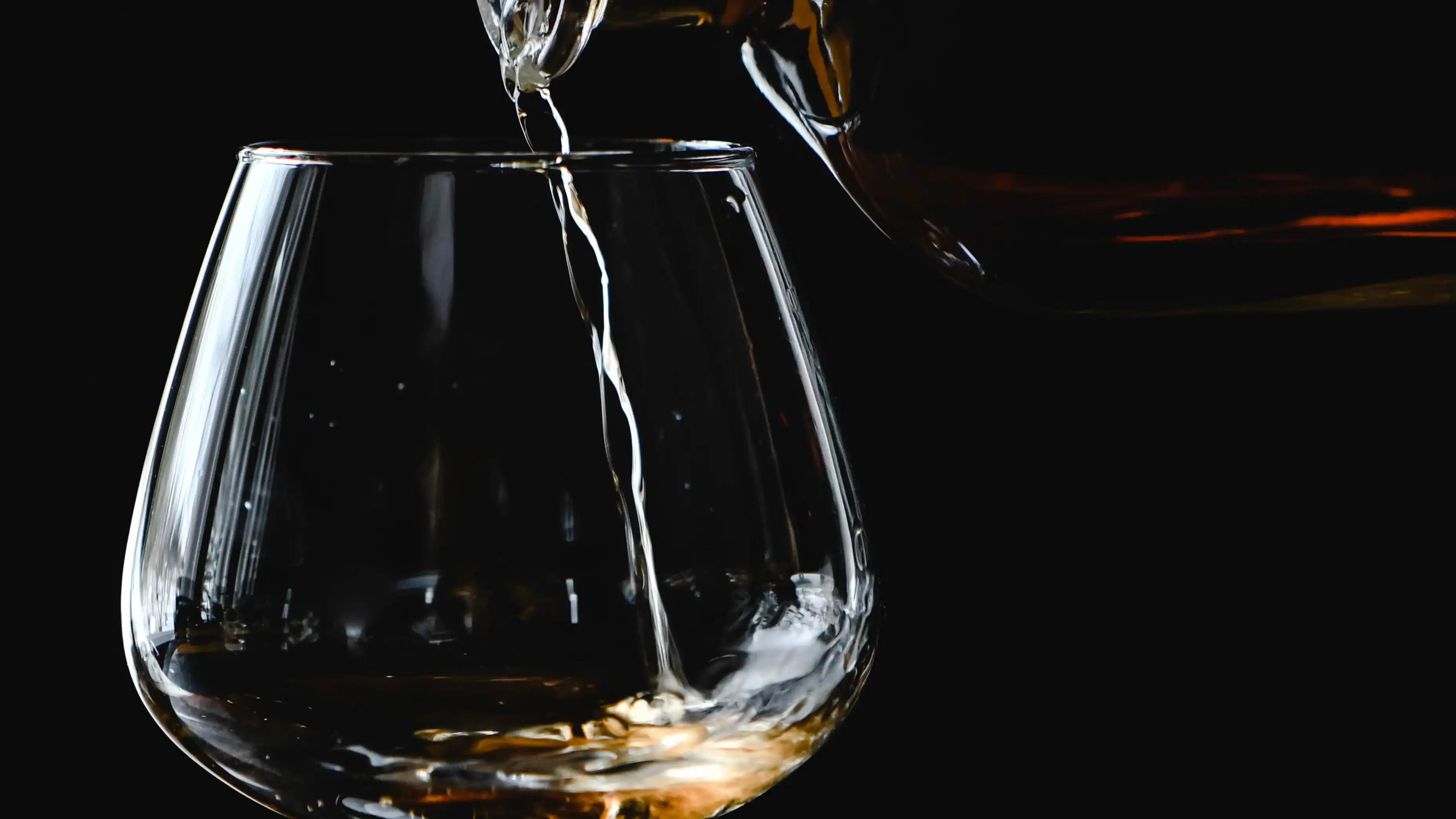 Una botella de Whisky sirviéndose sobre una copa Una botella de Whisky sirviéndose sobre una copa