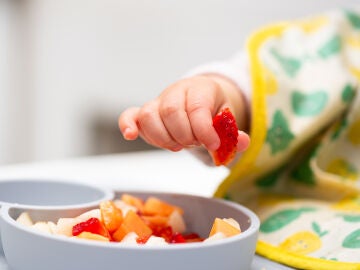 Mano del bebé con un pedazo de frutas