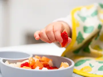 Mano del bebé con un pedazo de frutas Mano del bebé con un pedazo de frutas