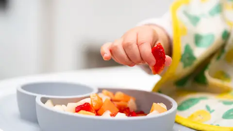 Mano del bebé con un pedazo de frutas