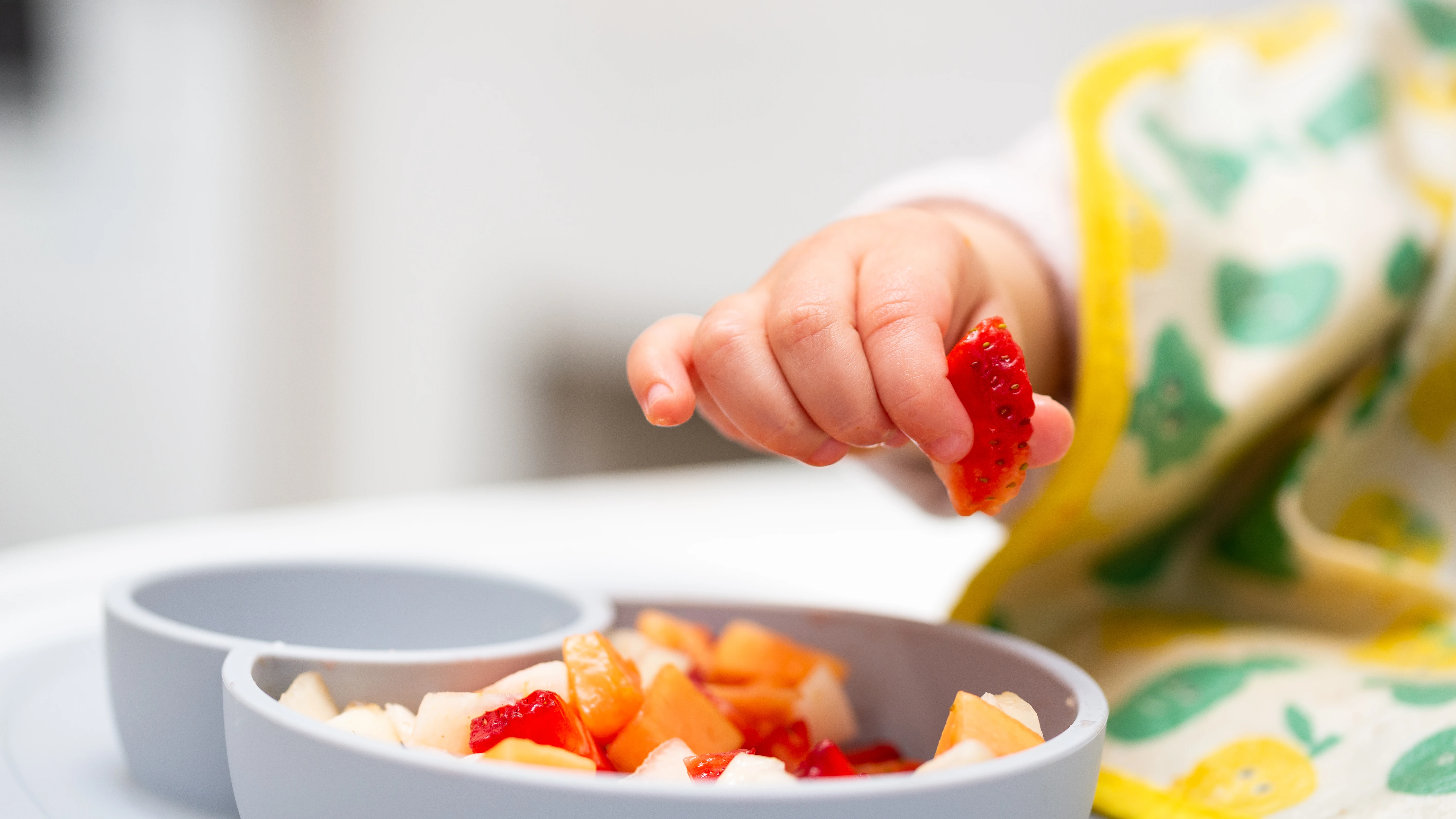 Mano del beb&eacute; con un pedazo de frutas