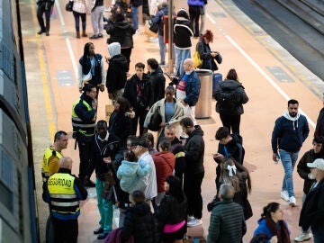 Imagen de varias personas en el andén de un tren de cercanías en la estación Almudena Grandes-Atocha Cercanías