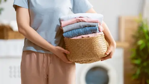 Una mujer con ropa limpia para guardar.