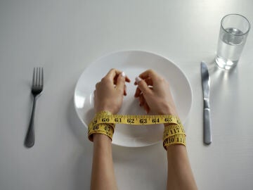 Persona atada con una cinta métrica a la hora de comer