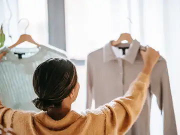 Una mujer revisa la ropa en perchas Una mujer revisa la ropa en perchas