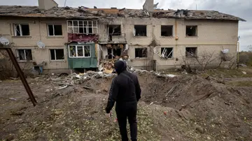 Un hombre observa el impacto de un misil ruso junto a un edificio de apartamentos
